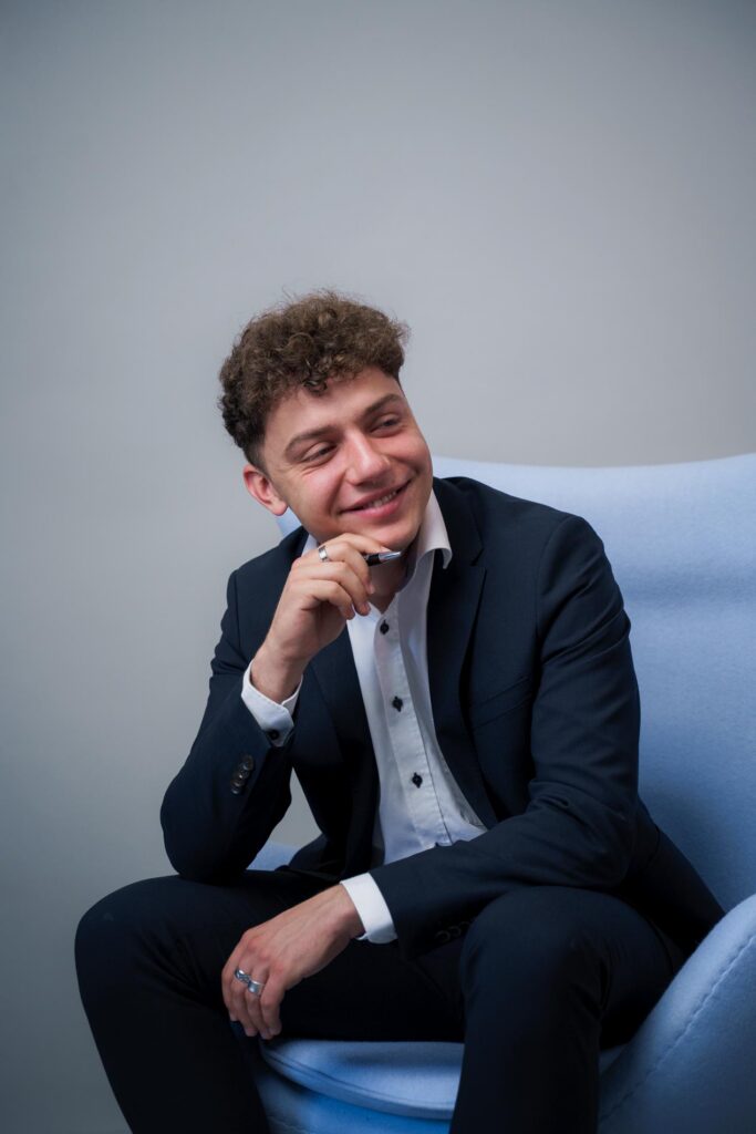 Bild zeigt freundliches Mitarbeiter Portrait sitzend auf einem Sessel