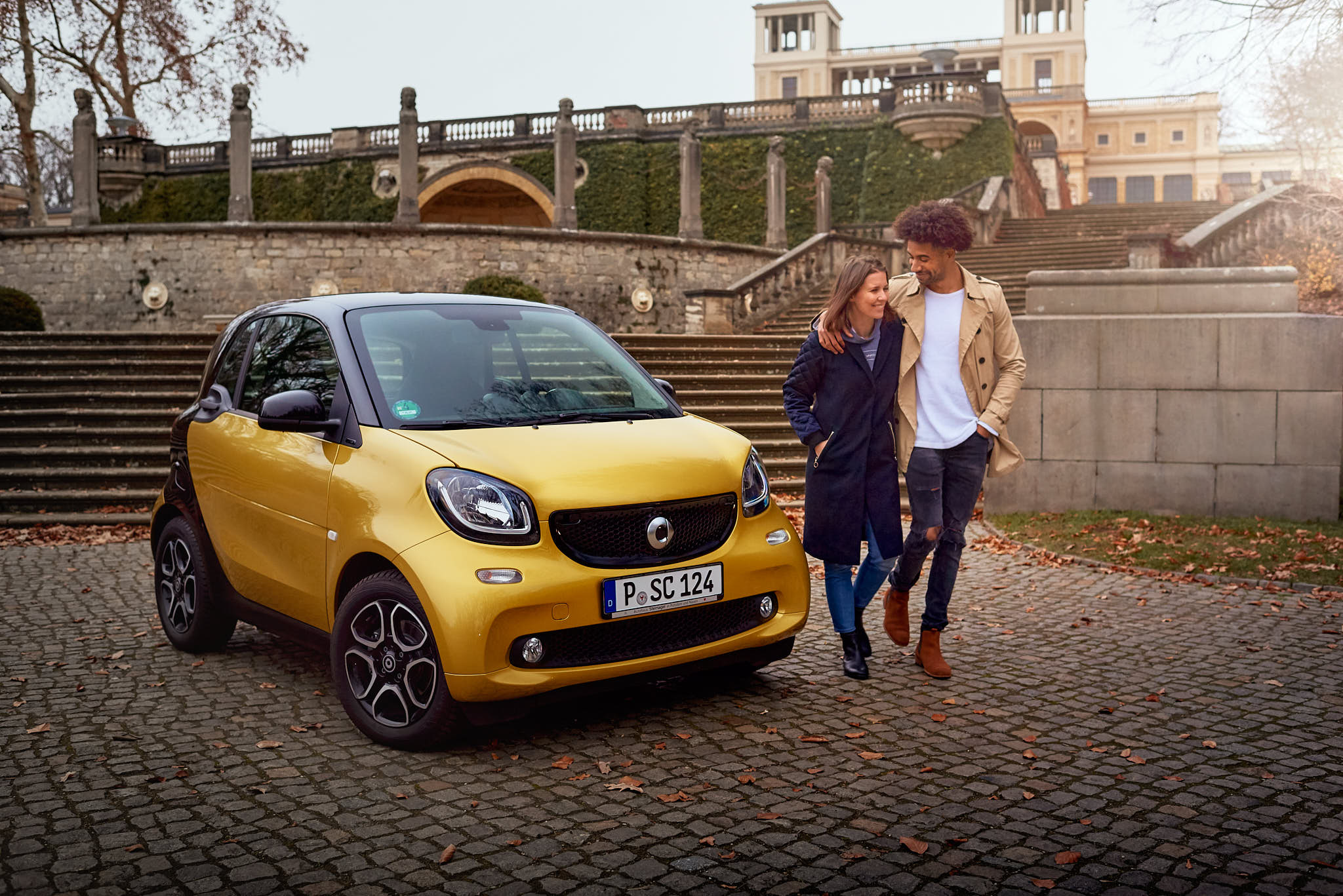 Portraitfotografie eines Paares mit dem Smart vor der historischen Kulisse von Sanssouci Potsdam