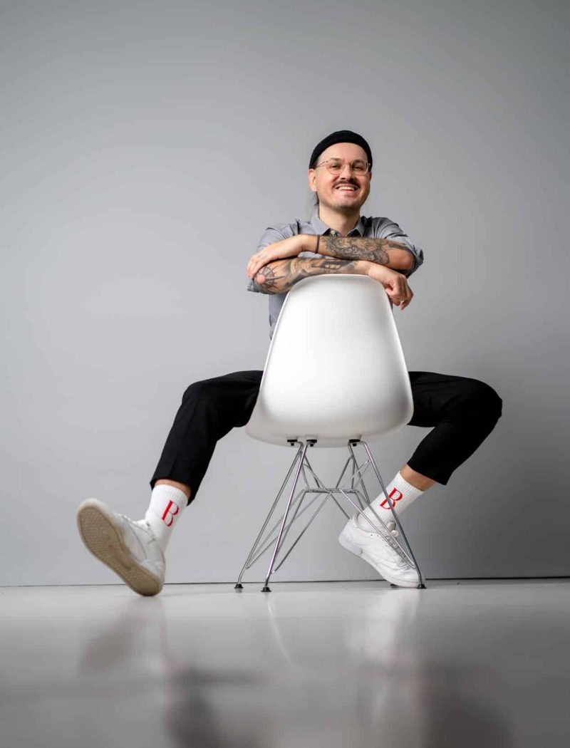 Business Portrait von Christoffer Brandt im Studio, lachend und verkehrt herum auf einem Stuhl sitzend