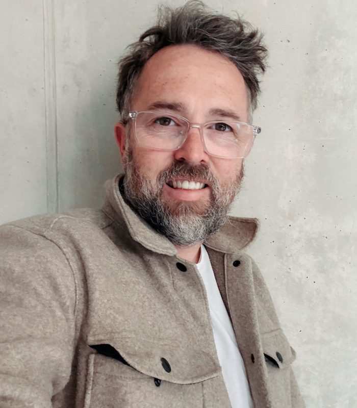 Fotograf Sascha Hoecker in seinem Studio vor einer Sichtbetonwand